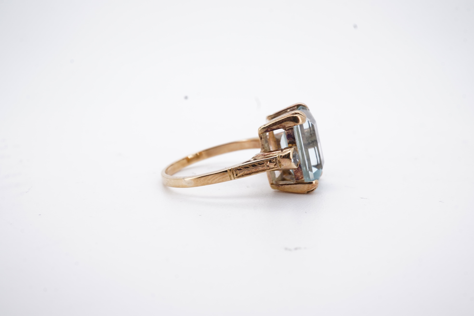 A yellow metal and single stone emerald cut aquamarine set ring, with two stone diamond set shoulders, size M, gross weight 4.2 grams.